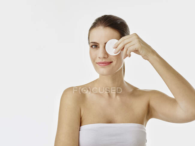 Portrait of smiling woman covering eye with cotton pad — Stock Photo