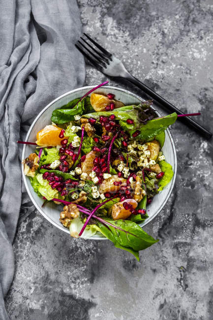 Winter salad with lettuce, tangerines, walnuts, feta and pomegranate seeds — Stock Photo