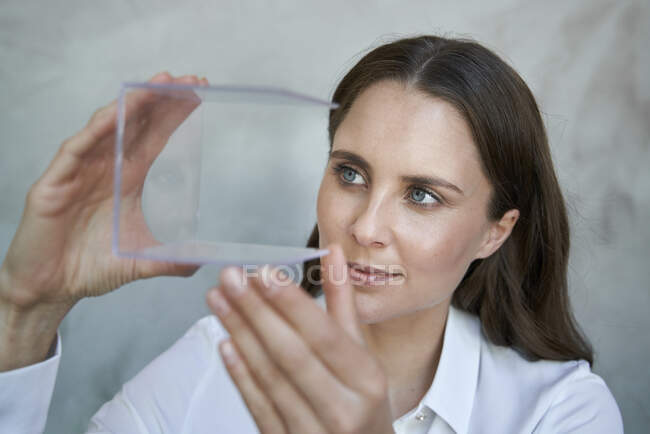 Retrato de mujer confiada mirando el cubo transparente - foto de stock