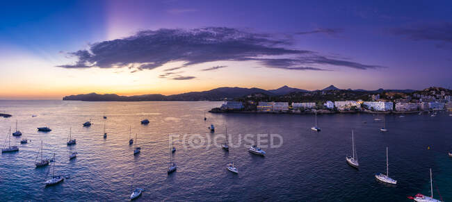 Espanha, Maiorca, Santa Ponsa, Panorama aéreo de barcos flutuando na água costeira ao anoitecer roxo com a cidade no fundo — Fotografia de Stock