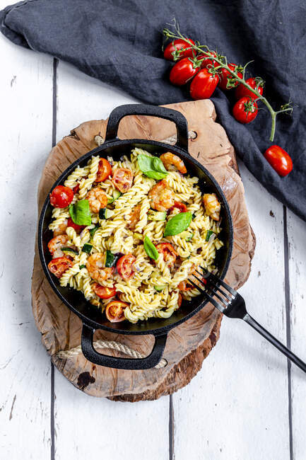 Pan of ready-to-eat pasta with tomatoes, shrimps, zucchini and basil — Stock Photo