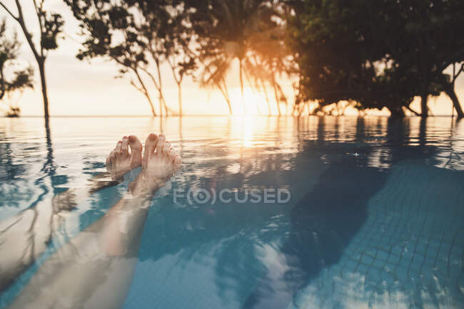 Ноги жінки в безкінечному басейні на заході сонця, Най Тон Біч, Пхукет, Таїланд — стокове фото