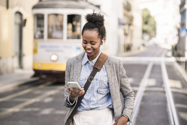 Посмішка молодої жінки з навушниками та мобільним телефоном у місті Лісабон (Португалія). — стокове фото
