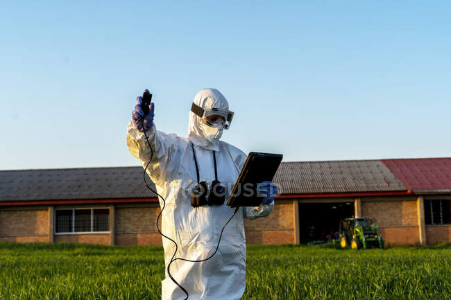 Científica investigando en el campo y utilizando un dispositivo de medición - foto de stock