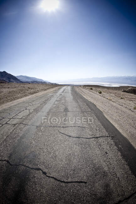 Etats-Unis, Californie, Le soleil brille sur une route fissurée dans la vallée de la mort — Photo de stock
