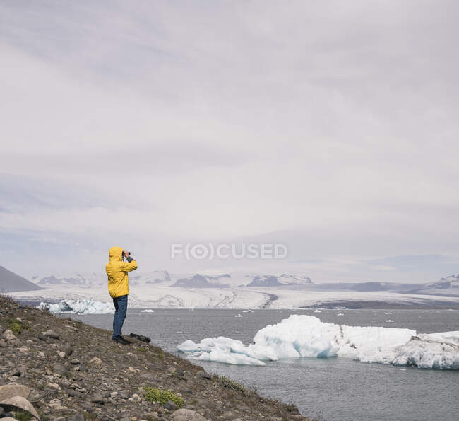 Homme mûr regardant le glacier Vatnajokull avec des jumelles, Islande — Photo de stock