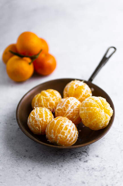 Freshly peeled mandarines on frying pan — Stock Photo