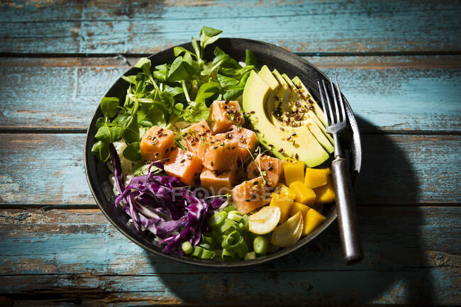 High angle view of poke bowl with fork on wooden table — Stock Photo