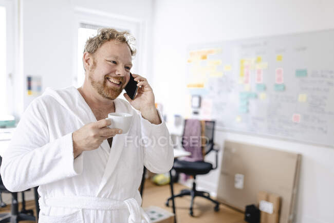 Empresário vestindo roupão de banho no escritório falando ao telefone — Fotografia de Stock