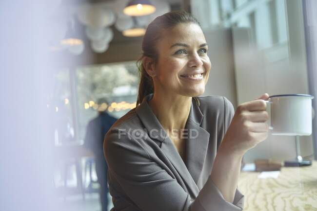 Empresária sorridente em um café bebendo café — Fotografia de Stock