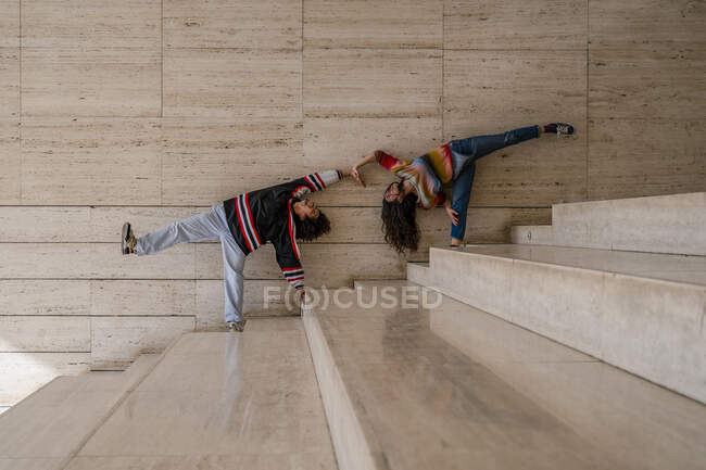 Casal de dançarinos em uma parede, levantando as pernas — Fotografia de Stock