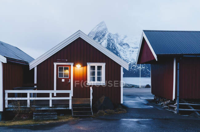 Cabaña roja iluminada en la costa, Hamnoy, Lofoten, Noruega - foto de stock