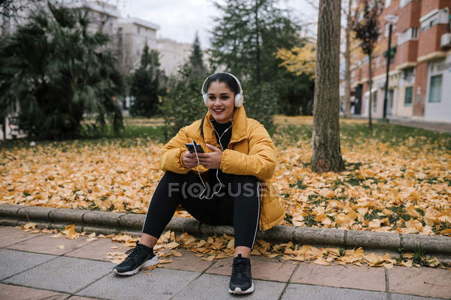 Portrait of smiling young woman  listening music with headphones and smartphone in autumn — Stock Photo
