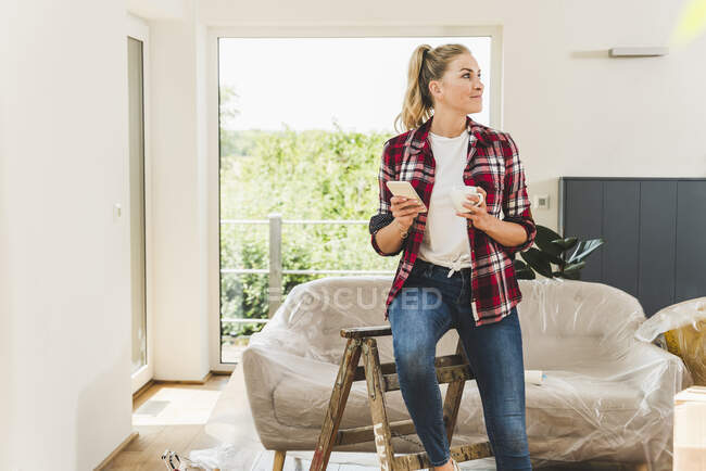 Mujer mudándose a casa nueva tomando un descanso para tomar café - foto de stock
