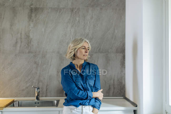 Portrait of pensive mature woman in kitchen at home — Stock Photo
