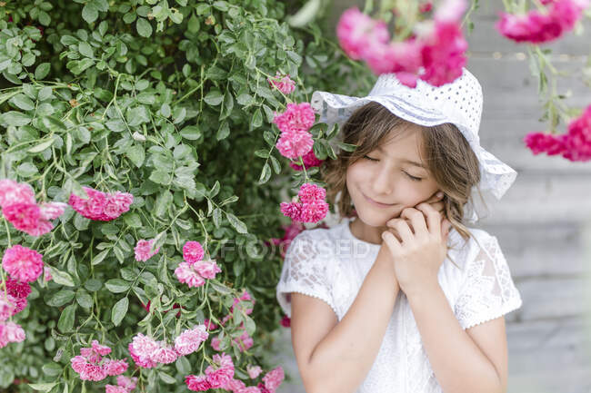 Ritratto di ragazza sorridente con gli occhi chiusi al rosebush — Foto stock
