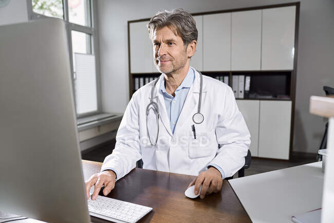 Medico che utilizza il computer alla scrivania nel suo studio medico — Foto stock