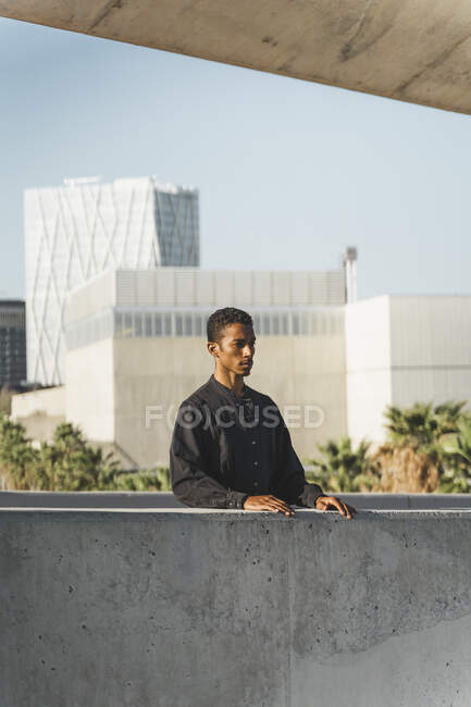 Young man wearing black kaftan behind a concrete wall — Stock Photo