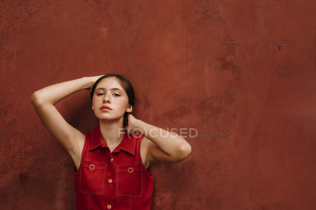 Portrait of female teenager wearing red strap dress in front of a wall — Photo de stock