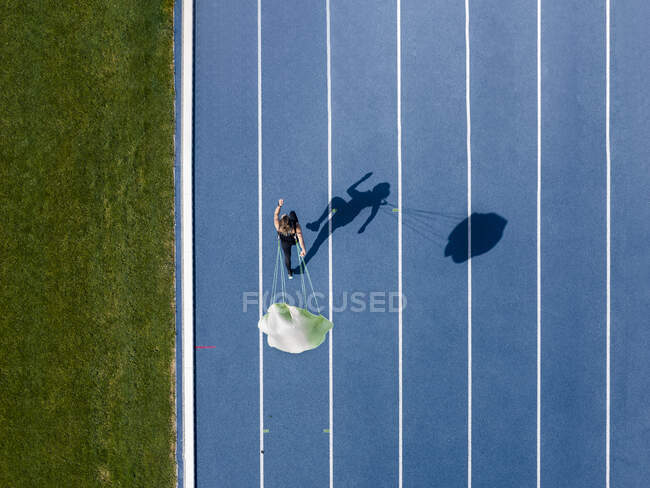Top view of female runner with parachute on tartan track — Stock Photo