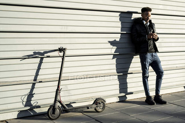 Uomo con smartphone ed e-scooter all'aperto — Foto stock