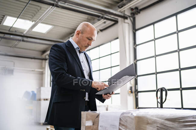 Empresário segurando uma pasta em uma fábrica — Fotografia de Stock