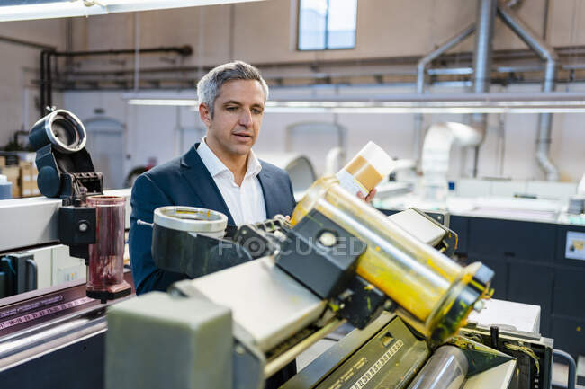 Empresário em uma fábrica olhando para uma máquina — Fotografia de Stock