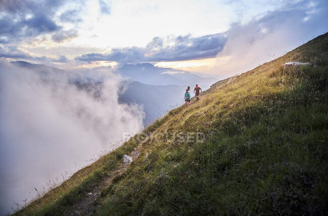 Homme et femme qui courent dans les montagnes — Photo de stock