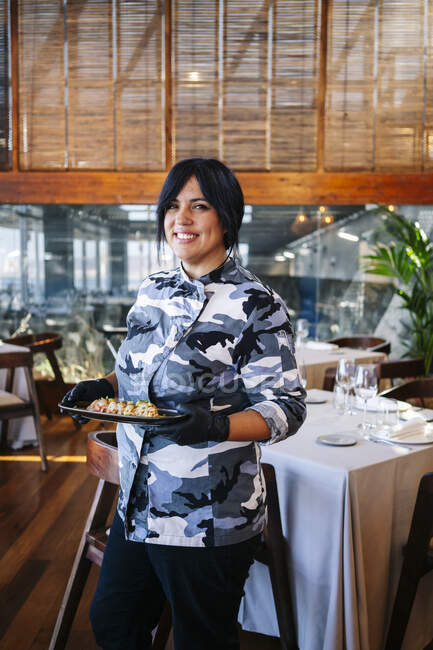 Портрет улыбающейся женщины, подающей блюдо в ресторане — стоковое фото