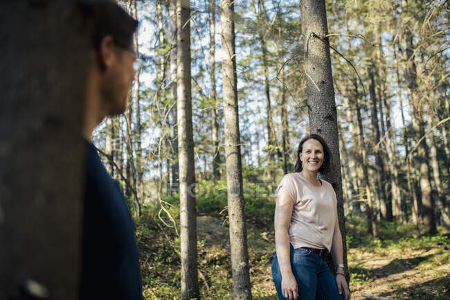 Mujer sonriente mirando al hombre en un bosque - foto de stock