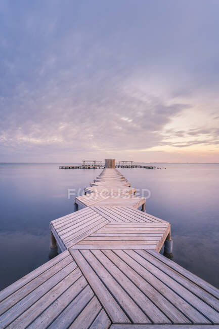 Spain, Murcia, Santiago de la Ribera, Wooden pier on calm sea at sunset — Stock Photo