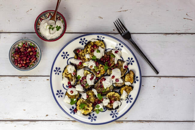 Baked eggplant slices with tahini, pomegranate seeds and parsley — Stock Photo