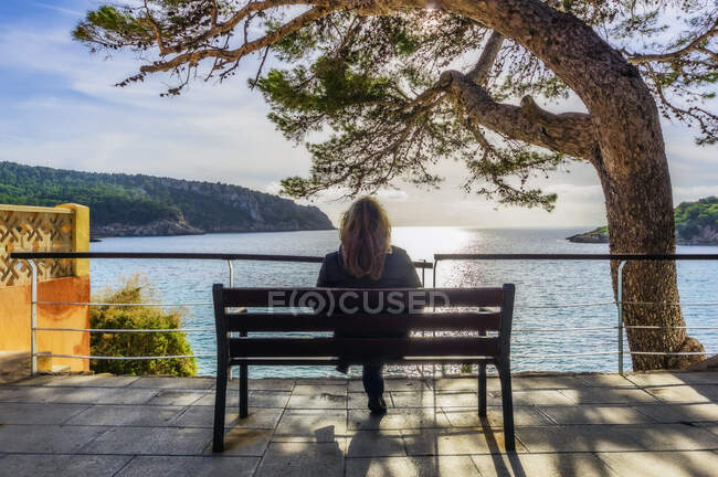 Espanha, Maiorca, Sant Elm, mulher sentada no banco, vista traseira — Fotografia de Stock