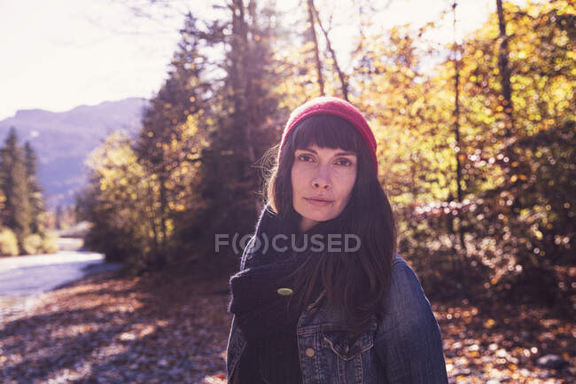 Donna con cappello di lana rossa e giacca di denim sul lungofiume in autunno — Foto stock