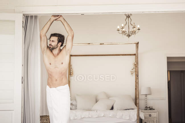 Shirtless young man standing at bedroom — Stock Photo