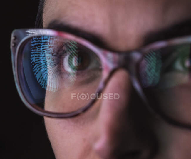 Mujer con un reflejo de una huella digital en sus gafas para representar identidad y acceso - foto de stock