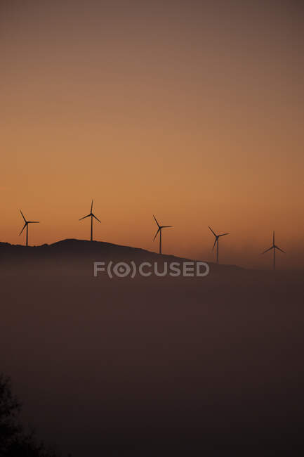 Испания, провинция Кадис, Тарифа, силуэты ветряных турбин, стоящих против угрюмого неба на туманном рассвете — стоковое фото