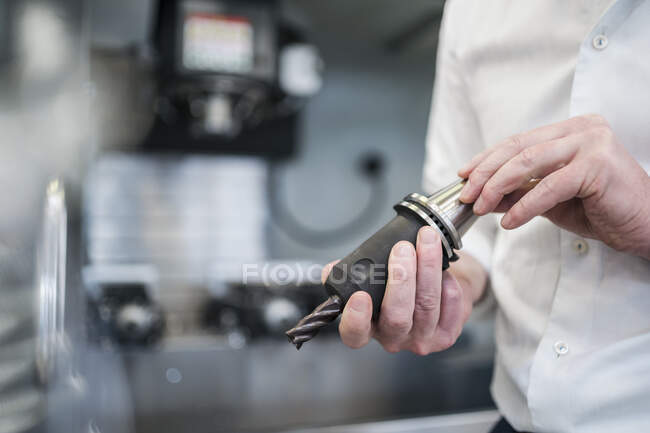 Close-up de homem segurando broca em uma fábrica — Fotografia de Stock