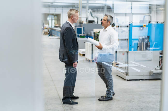 Due uomini d'affari che parlano in una fabbrica — Foto stock