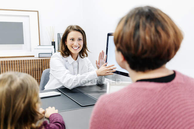 Arzt spricht mit Mutter mit Tochter am Schreibtisch in Arztpraxis — Stockfoto