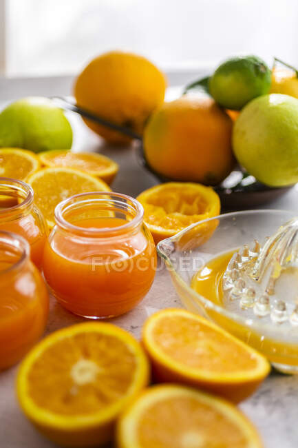 Свежевырезанные апельсины и банки апельсинового сока — стоковое фото