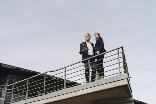 Uomo d'affari e donna d'affari in piedi su un balcone esterno edificio per uffici — Foto stock