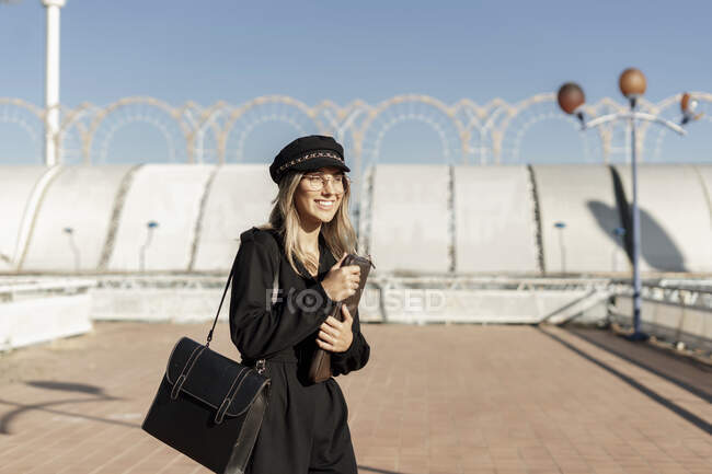 Молода блондинка у чорному капелюсі і сумці з ноутбуком. — стокове фото