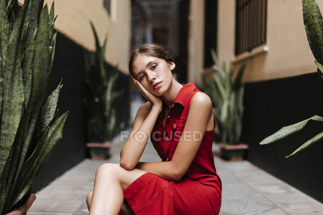 Portrait of female teenager wearing red strap dress in front of a wall — Foto stock