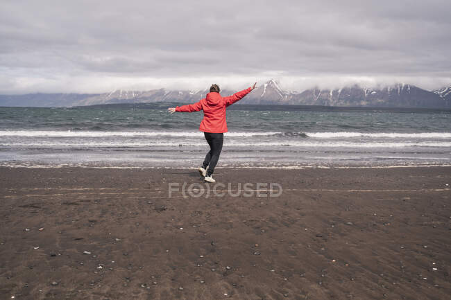 Giovane donna che balla sulla spiaggia di lava nel fiordo Eyjafjordur, Islanda — Foto stock