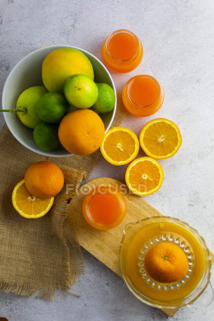 Presse-agrumes, agrumes mûrs et pots de jus d'orange fraîchement pressé — Photo de stock
