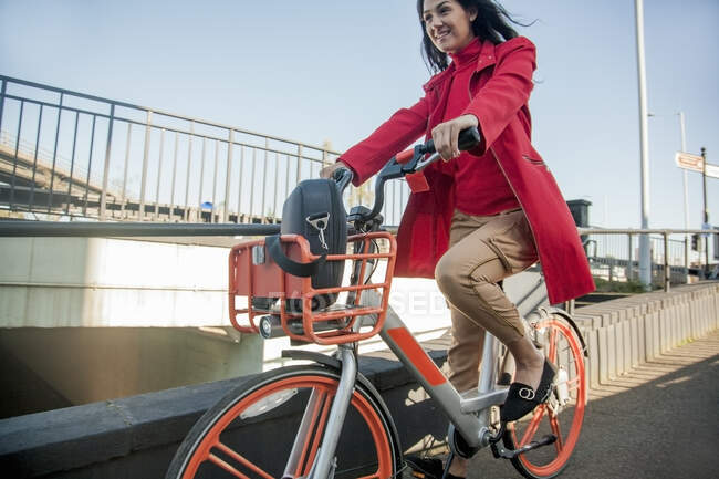 Jeune femme traversant la ville en vélo de location — Photo de stock