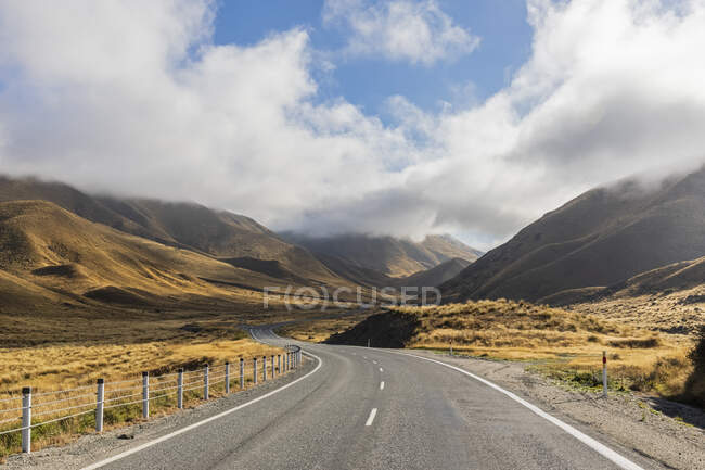 Neuseeland, Wolken über dem leeren State Highway 8 in Lindis Pass — Stockfoto
