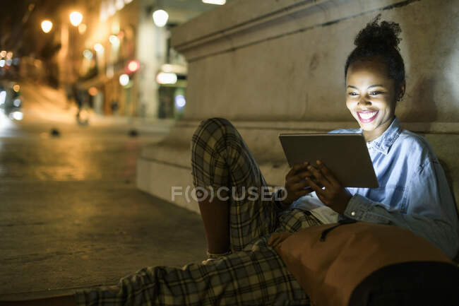 Portrait of happy young woman using digital tablet in the city by night, Lisbon, Portugal — Stock Photo