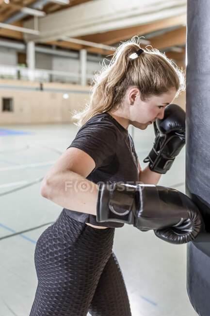 Женщина-боксер практикуется в боксерской груше в спортзале — стоковое фото